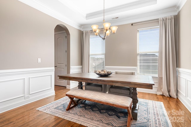 dining area featuring ornamental molding, an inviting chandelier, light hardwood / wood-style floors, and a tray ceiling