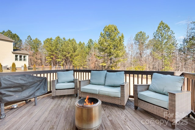 wooden deck featuring a grill and an outdoor living space with a fire pit