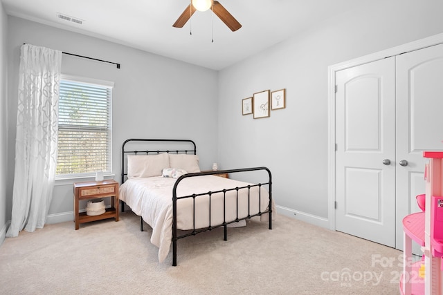 bedroom featuring light colored carpet, ceiling fan, and a closet