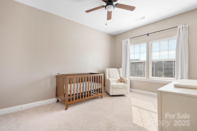 carpeted bedroom featuring a crib and ceiling fan