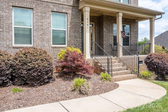 view of exterior entry featuring a porch and brick siding