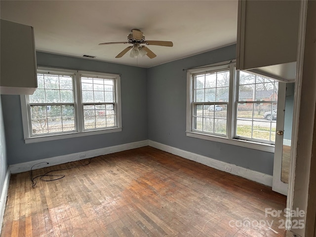 spare room featuring dark wood-type flooring, ceiling fan, and a healthy amount of sunlight