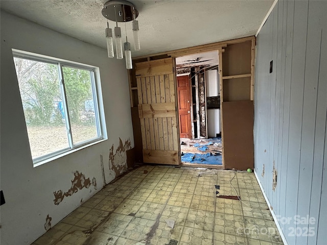 interior space with a textured ceiling and wood walls