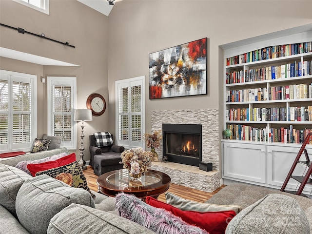 living room with hardwood / wood-style flooring, a stone fireplace, and a high ceiling