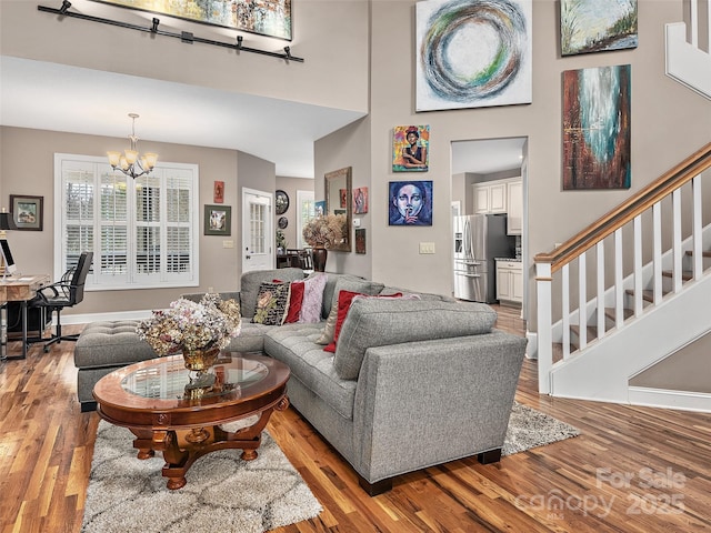 living room with a notable chandelier, a towering ceiling, and light hardwood / wood-style flooring