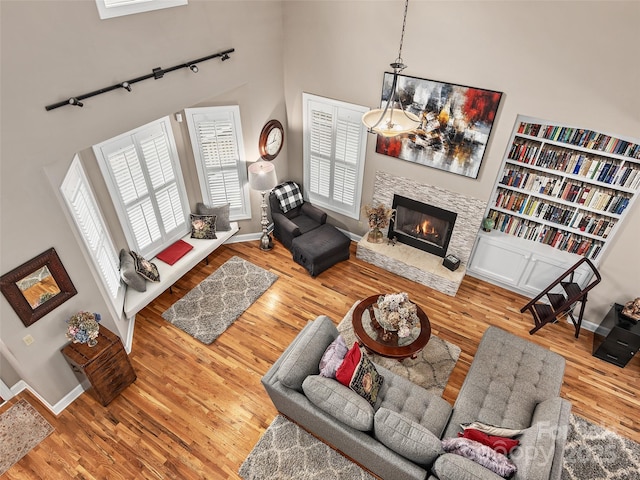 living room with hardwood / wood-style floors, a towering ceiling, and a stone fireplace