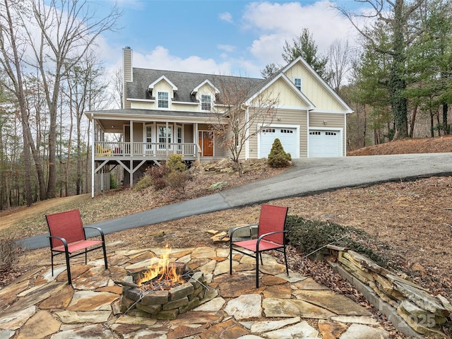 view of front of home featuring a garage, a fire pit, and covered porch