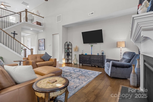 living room featuring a towering ceiling, dark wood-type flooring, and ceiling fan