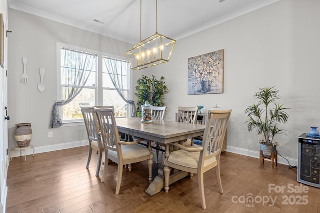 dining room with dark wood-type flooring, ornamental molding, and a chandelier