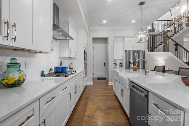 kitchen featuring white cabinetry, wall chimney range hood, a notable chandelier, and appliances with stainless steel finishes