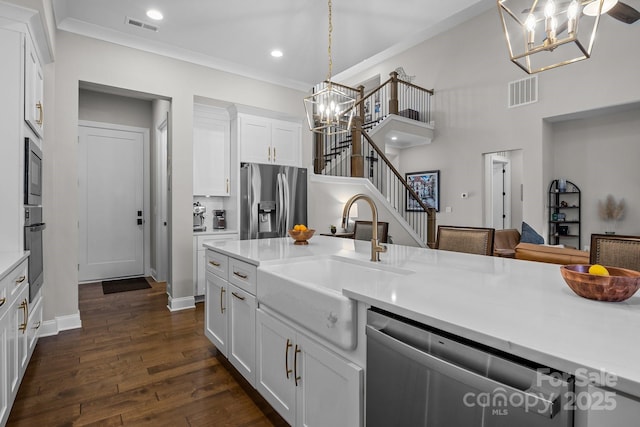 kitchen with stainless steel appliances, hanging light fixtures, white cabinets, and an inviting chandelier