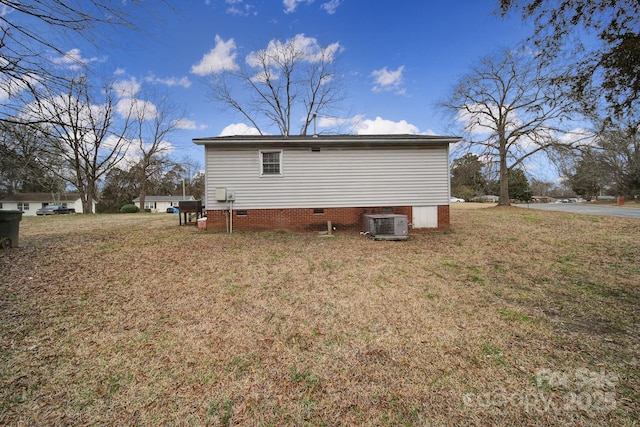 rear view of property featuring cooling unit and a yard