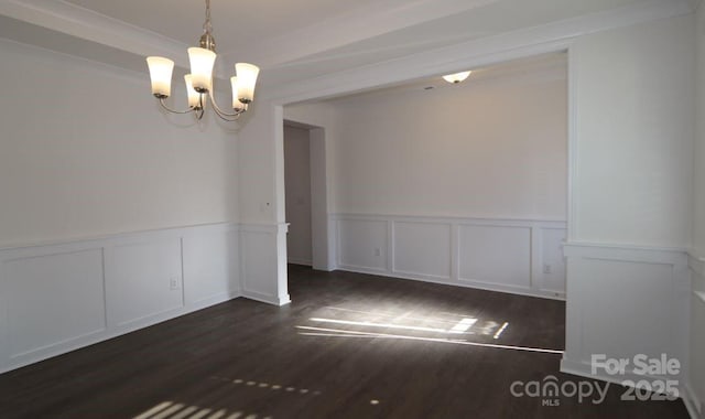 spare room with dark wood-type flooring and a notable chandelier