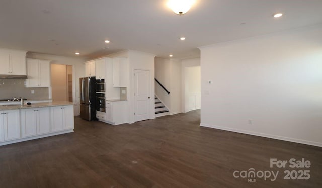 kitchen with white cabinetry, stainless steel fridge, backsplash, light stone countertops, and dark wood-type flooring