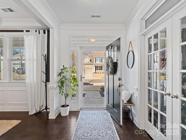 foyer featuring dark wood-type flooring, ornamental molding, and french doors