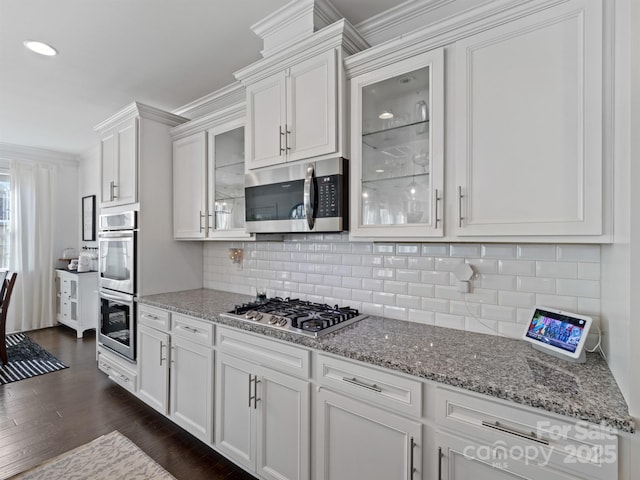 kitchen featuring crown molding, stainless steel appliances, dark hardwood / wood-style floors, tasteful backsplash, and white cabinets