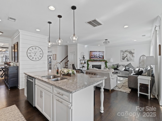 kitchen featuring dishwasher, an island with sink, sink, white cabinets, and light stone countertops