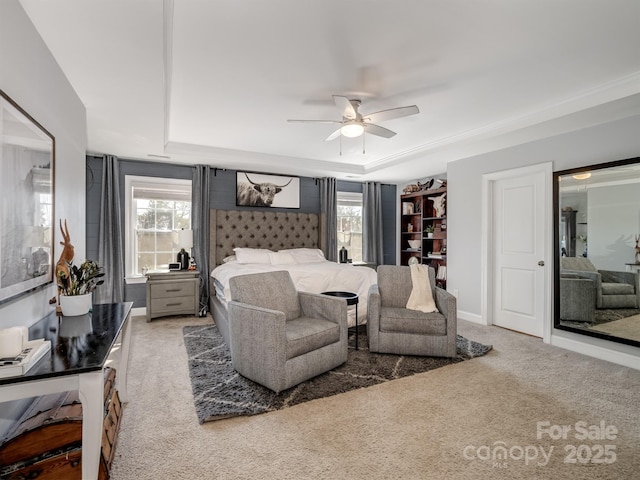 carpeted bedroom with ceiling fan and a raised ceiling