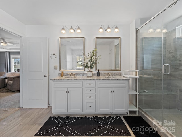 bathroom with hardwood / wood-style flooring, vanity, and a shower with door