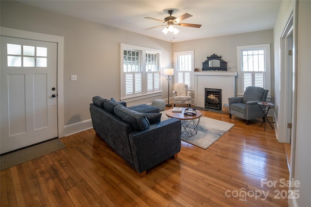 living room featuring hardwood / wood-style flooring, ceiling fan, a healthy amount of sunlight, and a fireplace