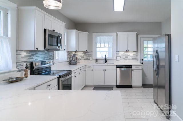 kitchen with sink, appliances with stainless steel finishes, light stone countertops, decorative backsplash, and white cabinets