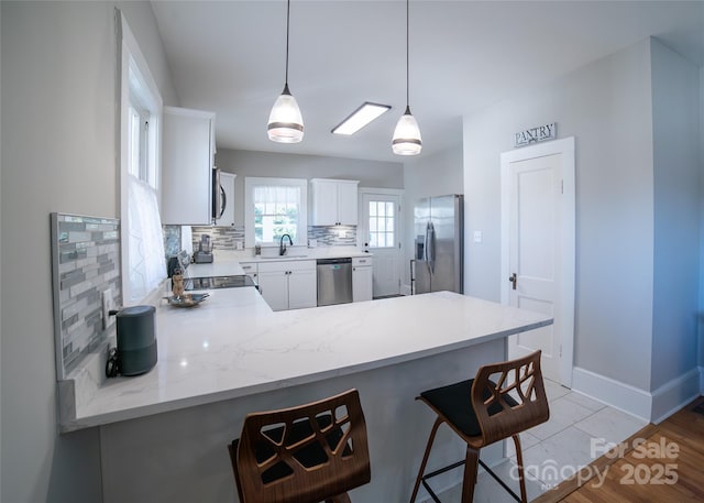 kitchen featuring sink, white cabinetry, hanging light fixtures, kitchen peninsula, and stainless steel appliances