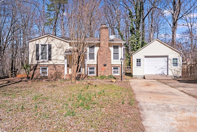 split foyer home featuring a garage, concrete driveway, an outdoor structure, and a chimney