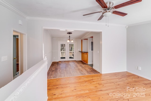 empty room featuring hardwood / wood-style flooring, baseboards, ornamental molding, and a ceiling fan