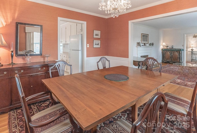 dining area featuring an inviting chandelier, crown molding, and light hardwood / wood-style flooring