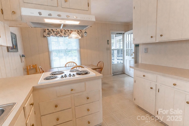 kitchen with crown molding, white stovetop, white cabinetry, decorative light fixtures, and wood walls