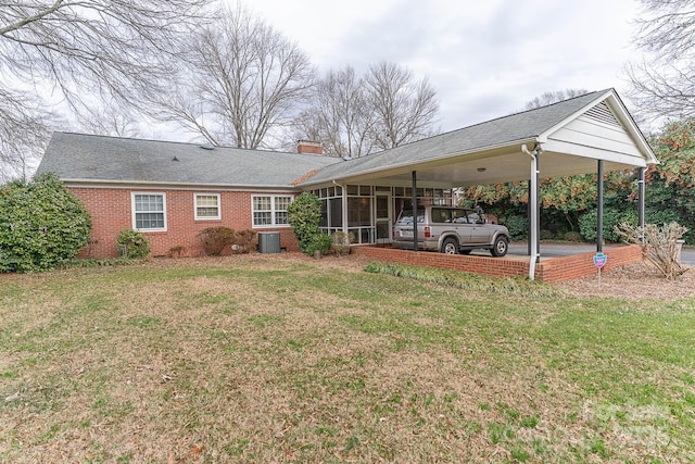 rear view of house with a carport, a lawn, and central air condition unit