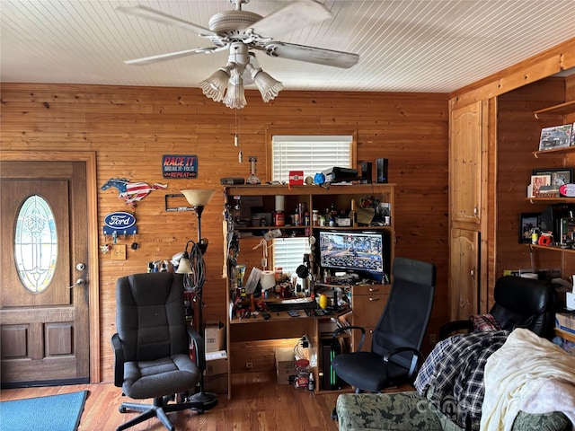 office space with wooden walls, ceiling fan, and wood finished floors