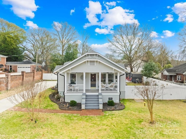 rear view of property featuring a porch, a garage, a yard, and an outbuilding