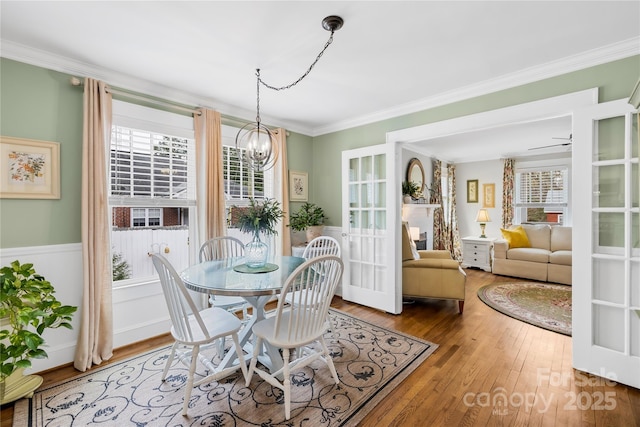 dining room featuring hardwood / wood-style floors, a wealth of natural light, ornamental molding, and a chandelier