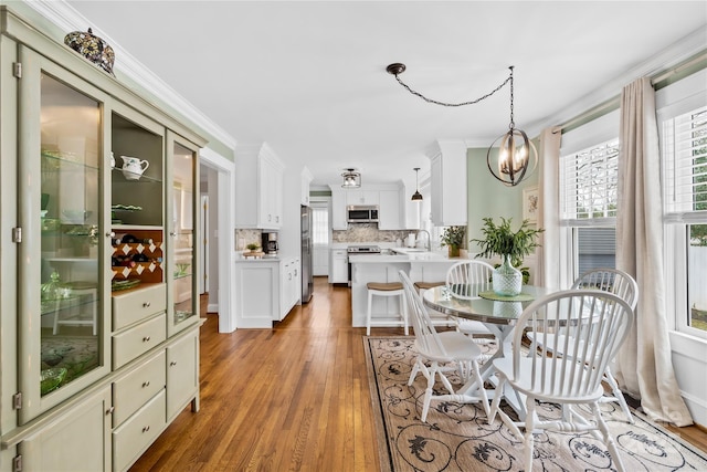 dining area featuring a notable chandelier, crown molding, light hardwood / wood-style floors, and sink