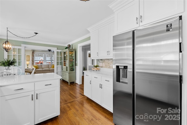 kitchen with tasteful backsplash, white cabinetry, stainless steel fridge, hardwood / wood-style flooring, and ornamental molding