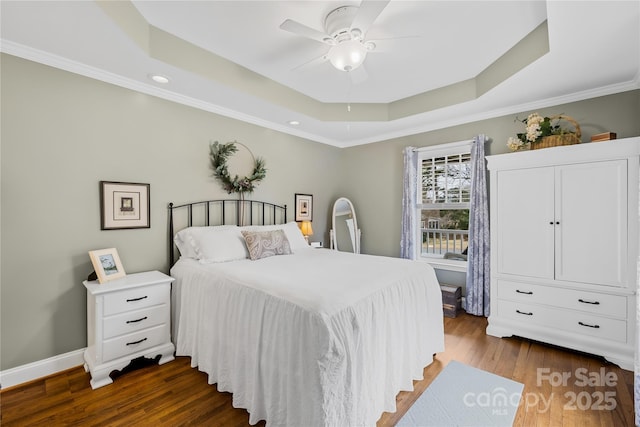 bedroom with a tray ceiling, ornamental molding, dark hardwood / wood-style floors, and ceiling fan