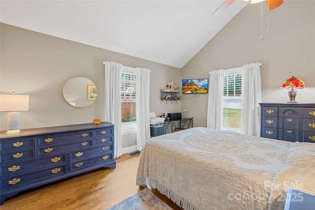 bedroom featuring multiple windows, high vaulted ceiling, ceiling fan, and light wood-type flooring