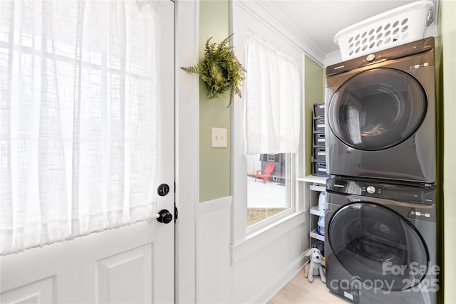 laundry room featuring stacked washing maching and dryer and crown molding