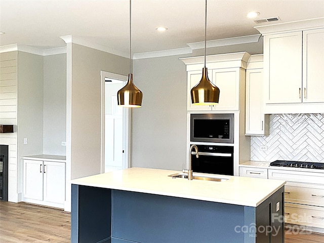 kitchen with pendant lighting, sink, stainless steel appliances, and a center island with sink