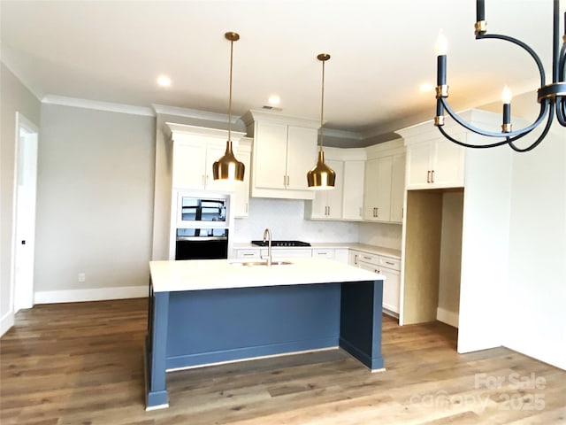 kitchen with built in microwave, wood-type flooring, an island with sink, oven, and white cabinets