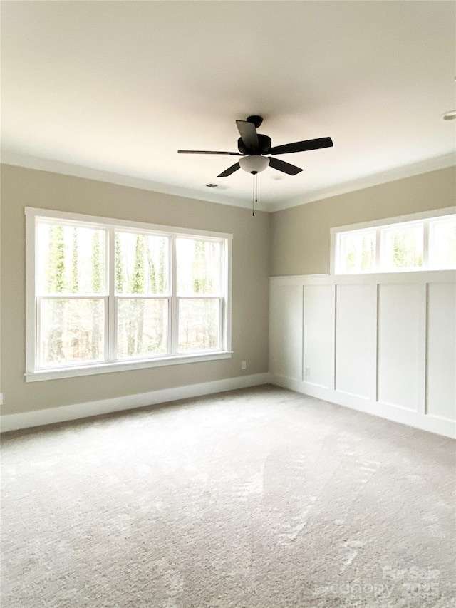 spare room with crown molding, light colored carpet, and ceiling fan