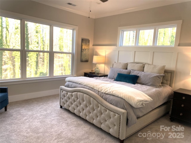 carpeted bedroom with ornamental molding, visible vents, a decorative wall, and multiple windows