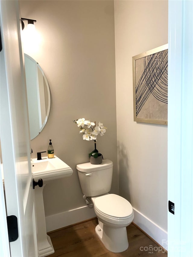 bathroom featuring toilet, baseboards, and wood finished floors