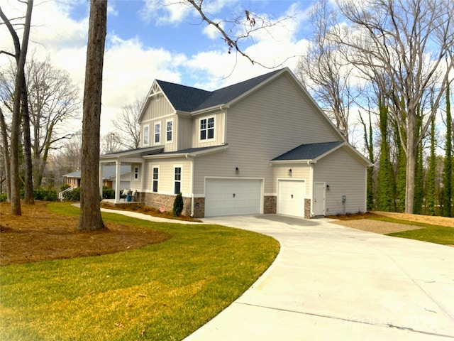 view of side of home featuring a garage, a yard, stone siding, driveway, and board and batten siding