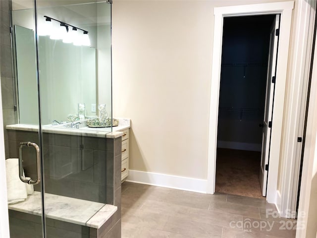 bathroom with baseboards, vanity, a shower stall, and tile patterned floors