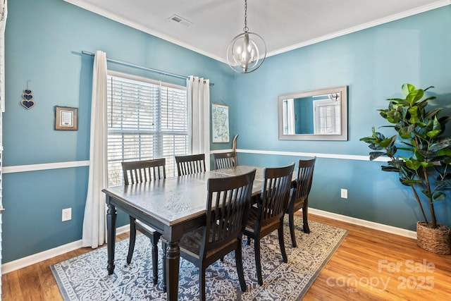 dining room with ornamental molding, wood-type flooring, and a notable chandelier