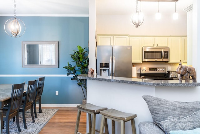 kitchen with appliances with stainless steel finishes, dark hardwood / wood-style flooring, a kitchen breakfast bar, hanging light fixtures, and crown molding