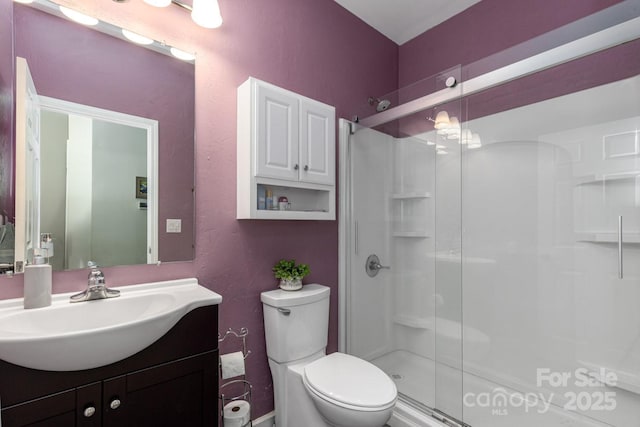 bathroom featuring vanity, a shower with door, and toilet