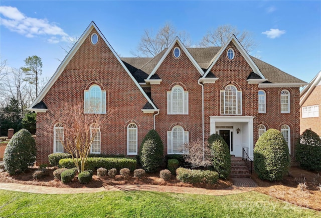 georgian-style home with a front yard and brick siding